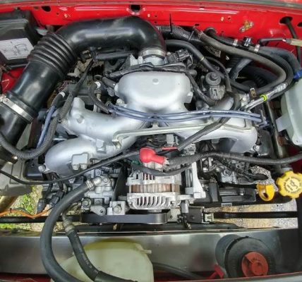Subaru conversion wiring harness bundled with color-coded wires connecting ECU to engine sensors in a VW Vanagon bay