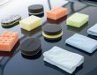 Assorted foam and microfiber polishing pads on a car hood for high-gloss finishing
