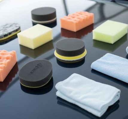 Assorted foam and microfiber polishing pads on a car hood for high-gloss finishing