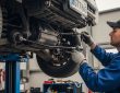 Mechanic inspecting front suspension and tie rods on a lifted vehicle for steering overcorrection diagnosis