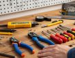 A beginner laying out home DIY electrical tools on a workbench, including a voltage tester, wire strippers, and insulated screwdrivers