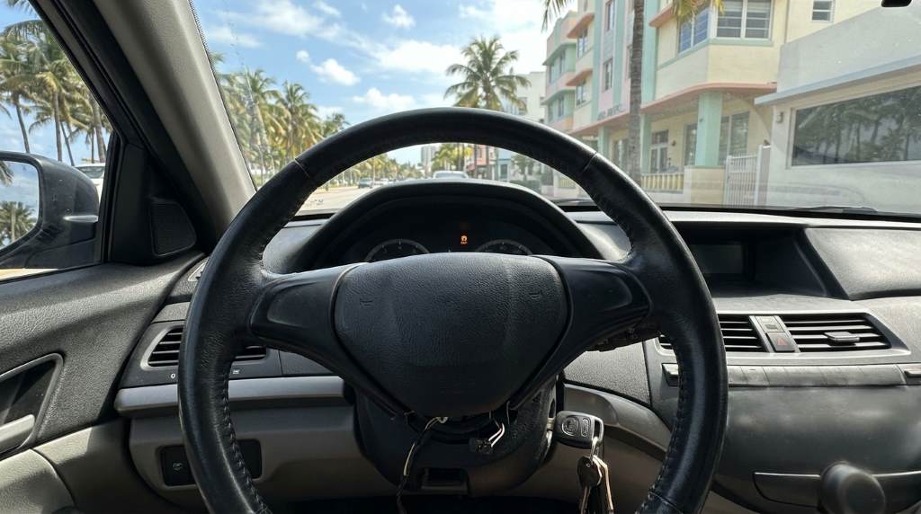 Car dashboard showing steering warning signs during heavy rain in Miami